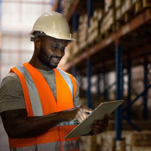 Warehouse worker using digital tablet to check inventory in storage room.